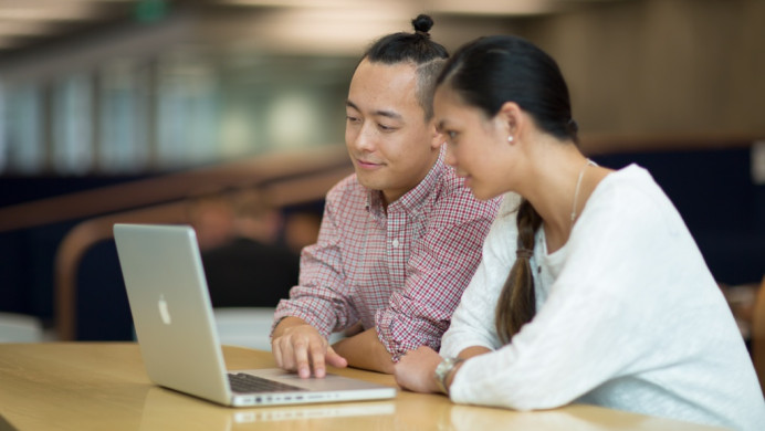 Two students look at a laptop