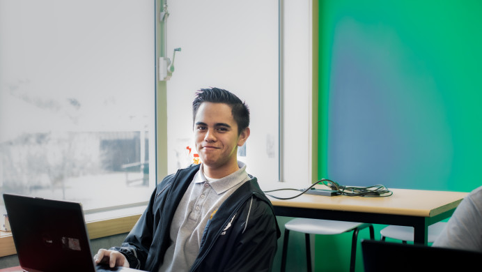 A student sits at a desk with their computer