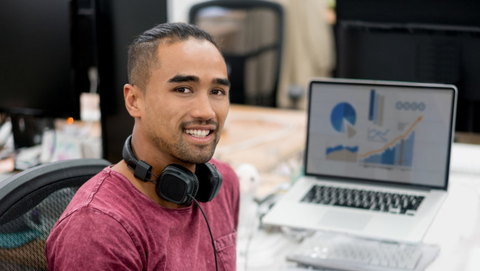 Man in front of computer smiles at camera