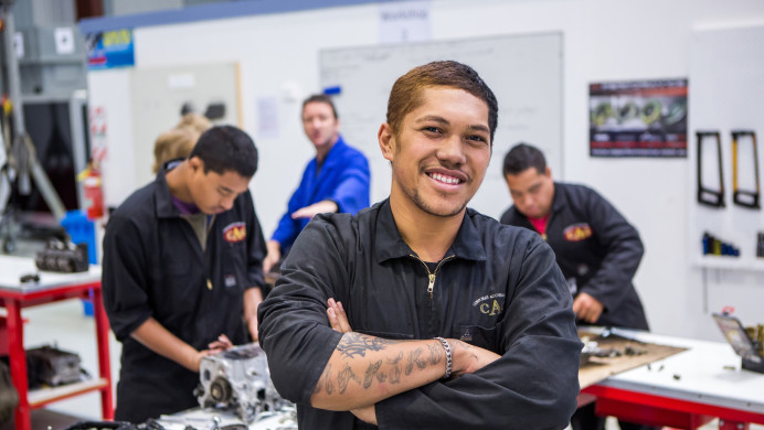 A young man stands in a workshop smiling