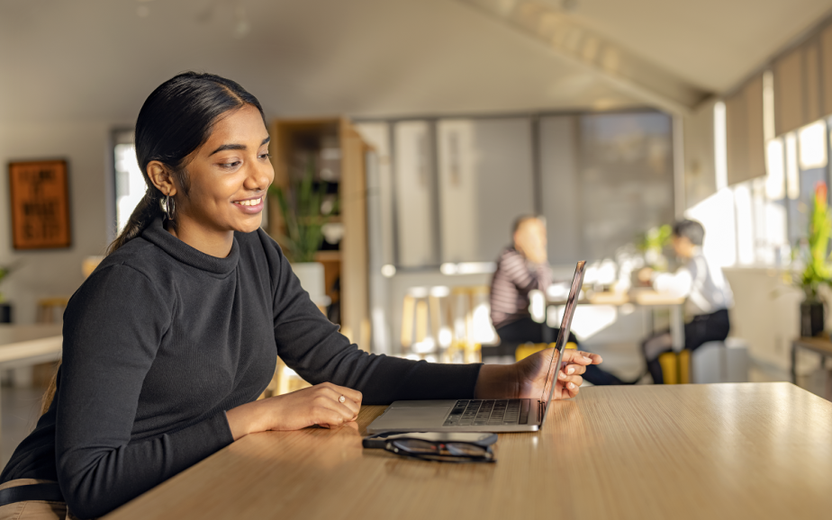 Woman smiles at laptop in a cafe