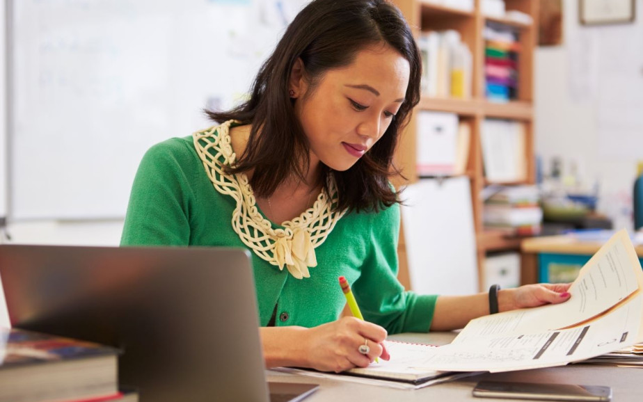 Teacher with papers in front of laptop