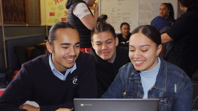 Three secondary students looking at a laptop 