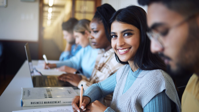 Students at a business management school sit at a desk