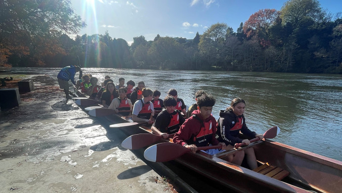 Students in a waka on a river.