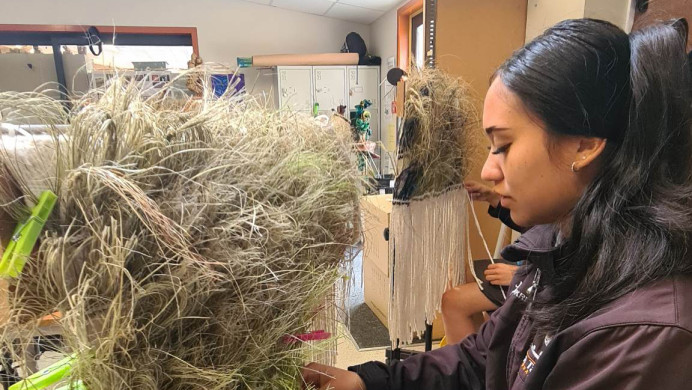 A young Māori woman doing weaving