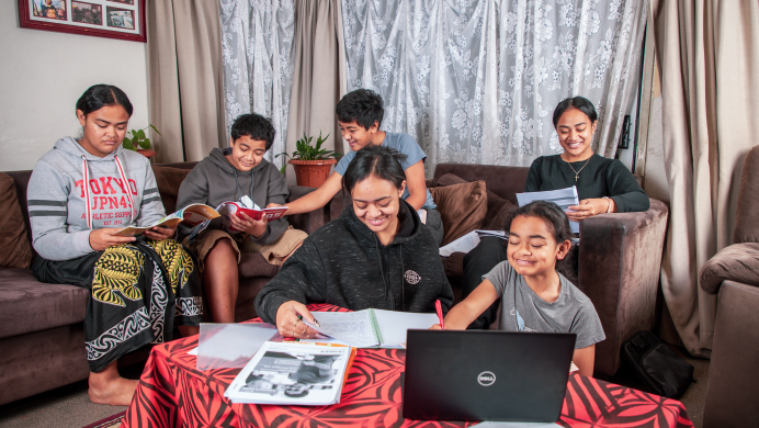 Six siblings are sitting around a table at home, they are all studying