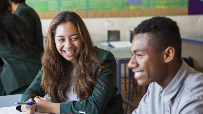 Two Pasifika students sit and a table with their study materials.