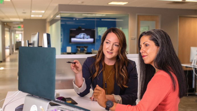 Two women look at a report on a computer