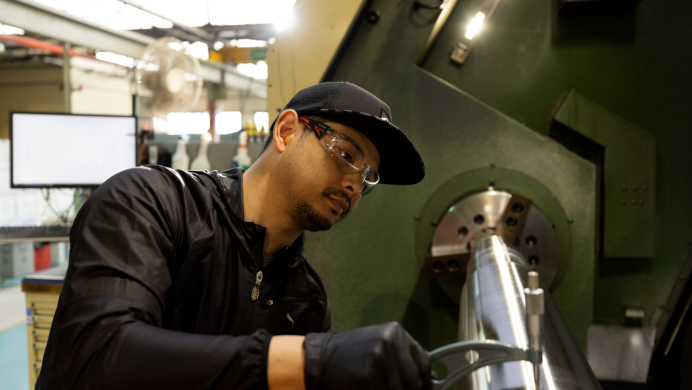 A manufacturing student operates a machine