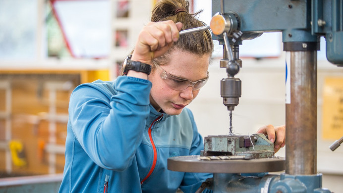 Young person drilling into metal