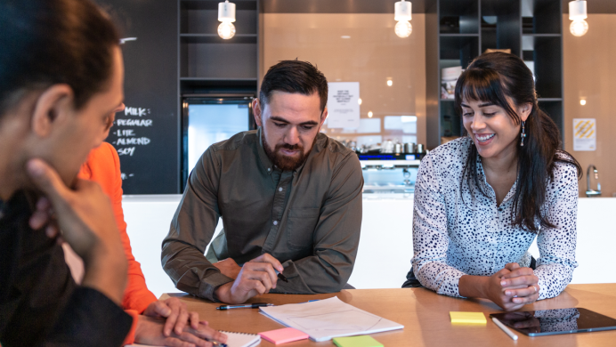 Three people sit at a table and consider paperwork