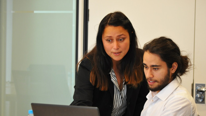 Two people look at a laptop