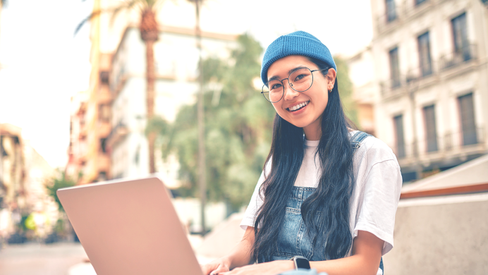 Student on laptop smiles at camera